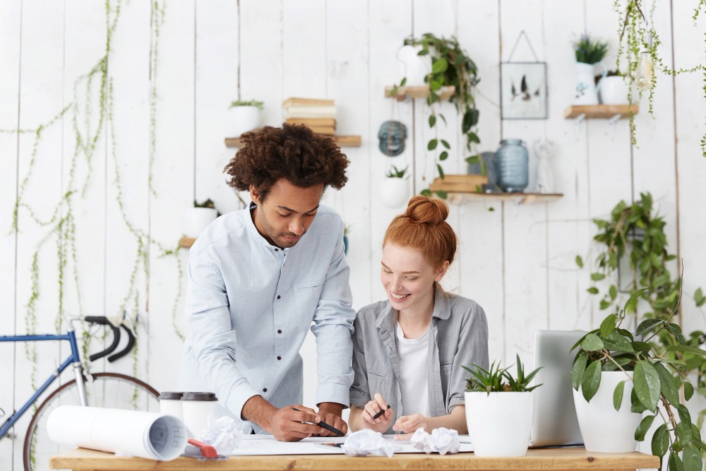 Um casal em uma mesa planejando cercados de plantas.