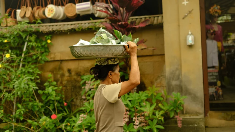 Mulher carregando a cesta com alimentos na vila em Bali